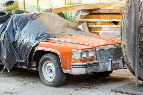 Eski arka bahçesinde Atölyesi, kapalı arabanı çarptım. Terk edilmiş Cabrio araç garaj kapıları yakınındaki siyah perde altında. Geri dönüşüm ve kullanımı.