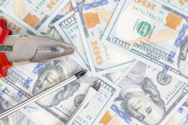 100 dolarlık banknotlar arka plan üzerinde yalan araçları. Pense ve tornavida bize karşı para. Düzeltme, sabitleme ve bütçe kavramı geliştirilmesi. Boşaltmak.