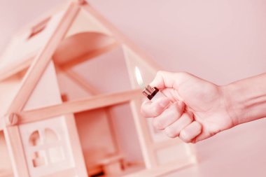 Arka plan üzerinde ahşap ev modeli karşı hafif yanma ile el. Evde kavramının kundakçılık. Suç kaza
