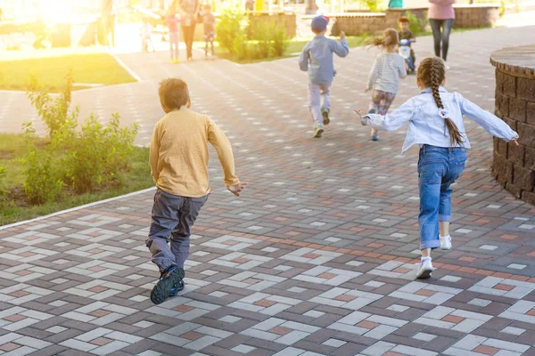 Grupo de crianças jogar catch-up correndo no parque da cidade. Crianças verão jogos ao ar livre e atividades esportivas — Fotografia de Stock