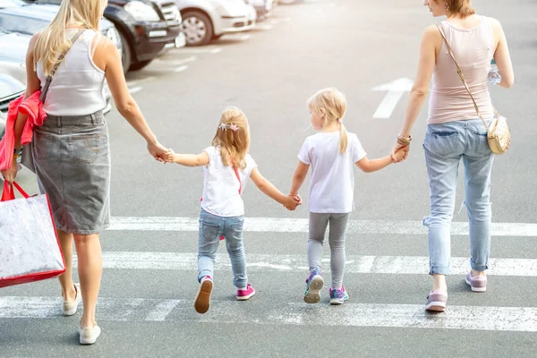 Grup birlikte yaya geçidi yürüyen dört kız arkadaşıyla. İki genç kadın ile iki kızı shopping mall yakınındaki açık havada eğleniyor. Çocuklar ve yetişkinler dostluk kavramı.