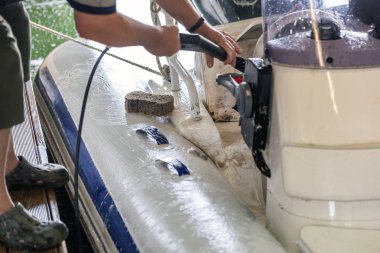 Adam beyaz şişme tekne Garage fırça ve basınç su sistemi ile yıkama. Gemi hizmet ve sezonluk bakım kavramı.