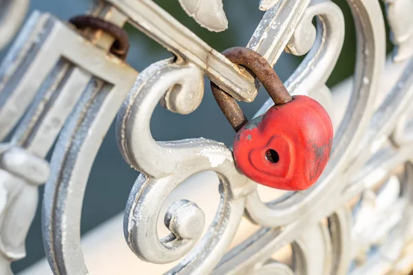 Red heart padlock locked on fence. Lock in shape of heart as symbol of eternal love.