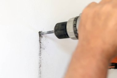 Matkap elinde tutan ve delik beyaz duvar yapım yakın çekim adam. DIY. Ev bina onarım ve yenileme