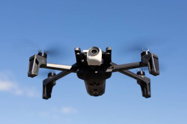 Küçük kompakt dron karşı açık mavi gökyüzü arka plan üzerinde parlak güneşli gün uçan..