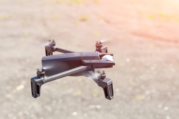 stock image Back view of Small compact drone flying against sun and clear sky on background on bright sunny day.