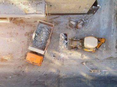 Buldozer yükleyici damperli kamyon inşaat sahasında içine atık ve enkaz yükleme. Bina sökülmesi ve inşaat elden çıkarma hizmet atık. Hava dron endüstriyel arka plan