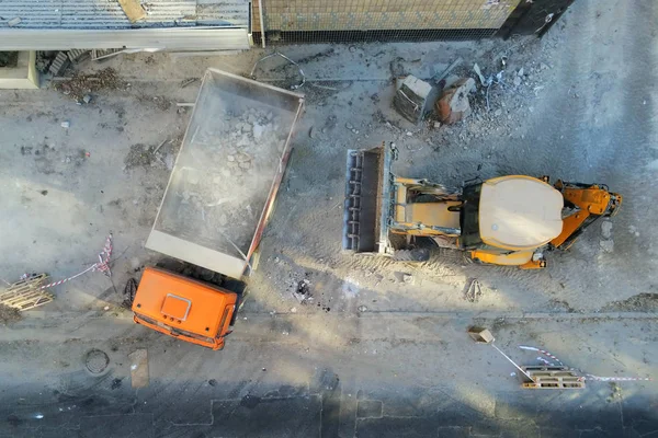 Buldozer yükleyici damperli kamyon inşaat sahasında içine atık ve enkaz yükleme. Bina sökülmesi ve inşaat elden çıkarma hizmet atık. Hava dron endüstriyel arka plan — Stok fotoğraf