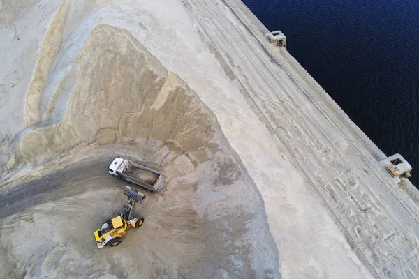 Великий навантажувач важких коліс завантажує пісок у сміттєвоз у піщану яму. Концепція важких промислових машин — стокове фото