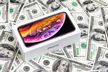 12 Ekim, 2018-Kiev, Ukrayna: en son Iphone Xs içinde açılmamış kutu üzerimize doları banknot arka plan. Apple smartphone kutusunu para faturaları üzerinde markalı. Çift kamera ve Oled ekran satışı ile modern becerikli alet.