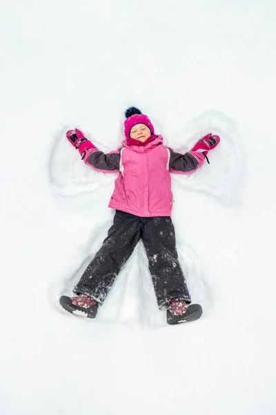 Милая Маленькая Девочка Теплом Лыжном Спортивном Костюме Делает Снежного Ангела — стоковое фото