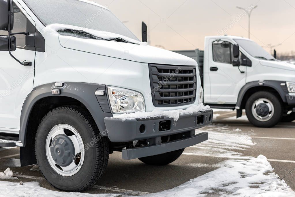 New middle size trucks at dealership parking outdoors at winter. Truck service and maintenance. Delivering and warehouse service.