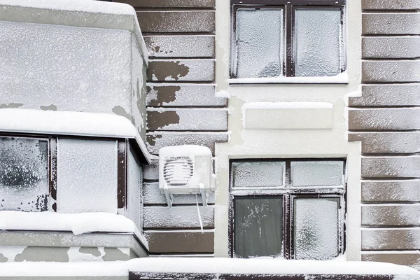 Building facade of modern high-rise apartment house covered with snow and frost after heavy windy snowstorm Snowfall and blizzard aftermath in winter. Cold snowy weather forecast.