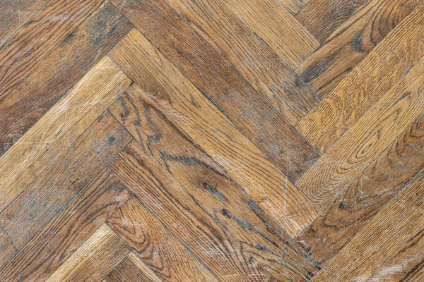 Old aged dirty herringbone parquet background. Natural weathered scratched oak hardwood texture.
