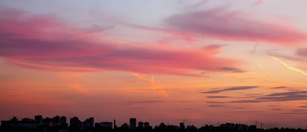 Stadtbild mit dramatischem Sonnenuntergang. Silhouette von Gebäuden und Kränen auf der Baustelle. städtische Industriestadt Hintergrund — Stockfoto