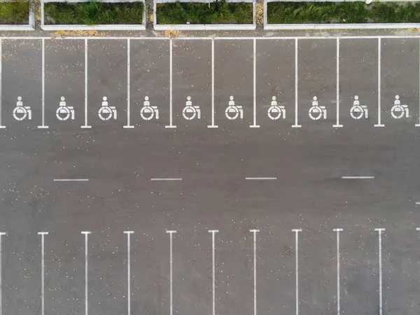 Άδειο υπαίθριος χώρος στάθμευσης με ανάπηρο σύμβολο εικονίδιο. Prking μέρη δεσμεύονται για άτομα με ειδικές ανάγκες. Δείτε τον εναέριο κηφήνα — Φωτογραφία Αρχείου