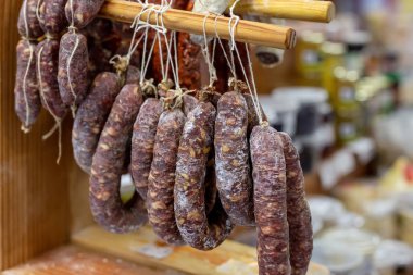 Yerel çiftçi Market ahşap raf üzerinde çeşitli lezzetli kurutulmuş sosis astı. Kasap dükkanındaki taze lezzetli et Şarküteri.