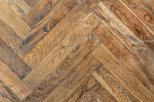 Old aged dirty herringbone parquet background. Natural weathered scratched oak hardwood texture.