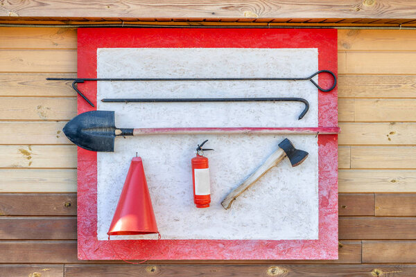 Настенный пожарный щит с противопожарными инструментами. Лопата, крюк, топор, конусное ведро, огнетушитель и другое оборудование, повешенное на огневой точке
.