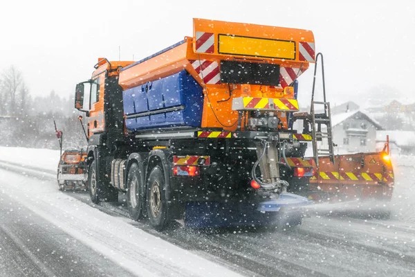 Snowplow truck removing dirty snow from city street or highway during heavy snowfalls. Traffic road situation. Weather forecast for drivers. Seasonal road maintenance.