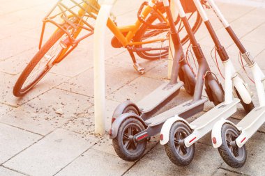 Bisiklet ve elektrikli scooter şehir cadde üzerinde park etmiş. Sokak taşıma self-servis Kiralama Servisi. Smartphone uygulama ile kentsel araç kiralamak. Sıfır emisyon yeşil eko enerji.