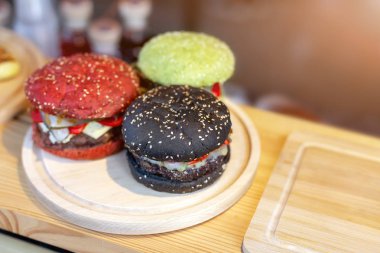 Üç lezzetli parlak renkli sığır eti burgers gıda fest ahşap kasada. amburger topuz clolred ile domates, fesleğen ve mürekkep balığı mürekkep