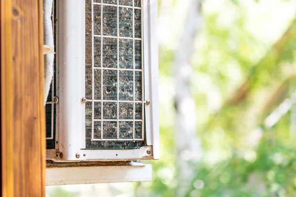 Close-up outdoor air condition unit with clogged obstructed compressor radiator grill. Details of air conditioner needed to clean and maintenance. House climate system check up and service