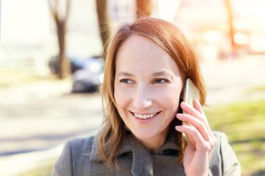 Genç Yetişkin mutlu beyaz wooman Smartphone açık havada konuşurken gülümseyen