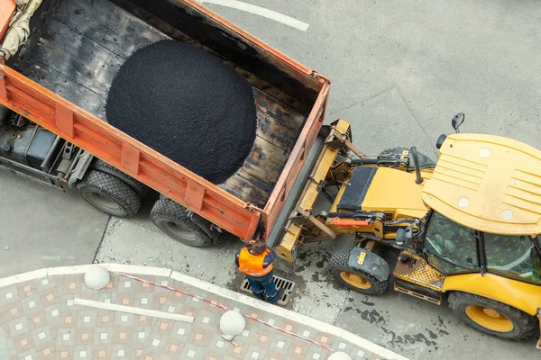 Ağır endüstriyel çöp kamyonu sıcak asfaltı boşaltıyor. Şehir yol yapımı ve yenilenme alanı. — Stok fotoğraf