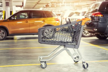 Modern plastik alışveriş sepeti sol alışveriş merkezi çatılı yer altı otoparkı, boş. Arka plan üzerinde bulanık park edilmiş arabalar ile süpermarket arabası. Rahat rahat ve alışveriş İmkanları