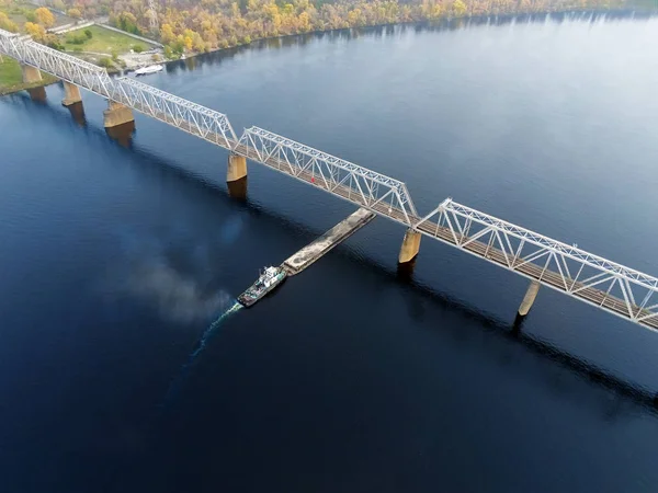 Paesaggio aereo panoramico di Kiev e del fiume Dnipro al tramonto. Rimorchiatore che sostiene chiatta con materiali sfusi di sabbia diretti verso il fiume Dnieper. Navigazione interna ucraina e merci fluviali — Foto Stock