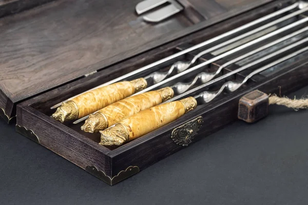 Close up handles Big luxury stainless steel skewers set in wooden box for grill and barbecue. Expensive high quality exlusive gift for man hunter