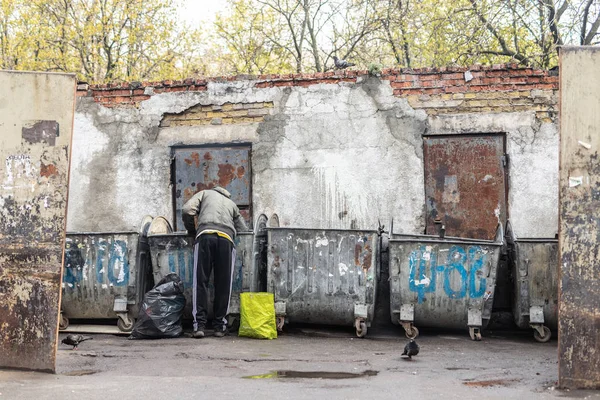 Киев, Украина - 20 апреля 2019 года: Бездомный попрошайка ищет еду в мусорных контейнерах на городской улице. Безработица и бедность — стоковое фото
