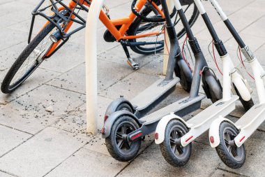 Bisiklet ve elektrikli scooter şehir cadde üzerinde park etmiş. Sokak taşıma self-servis Kiralama Servisi. Smartphone uygulama ile kentsel araç kiralamak. Sıfır emisyon yeşil eko enerji