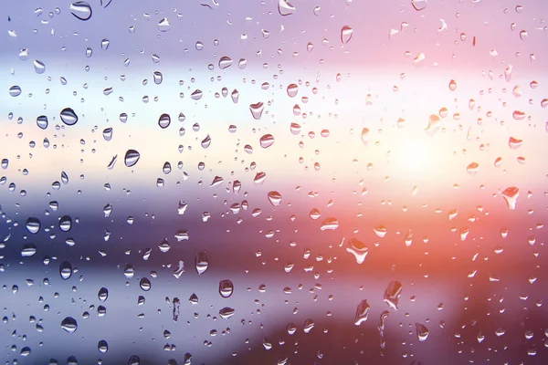 Druppels water op venster glas na regen met dramatische wazig zonsondergang op de achtergrond. Idyllische rustige natuur behang. Weerbericht. Seizoensneer slag — Stockfoto