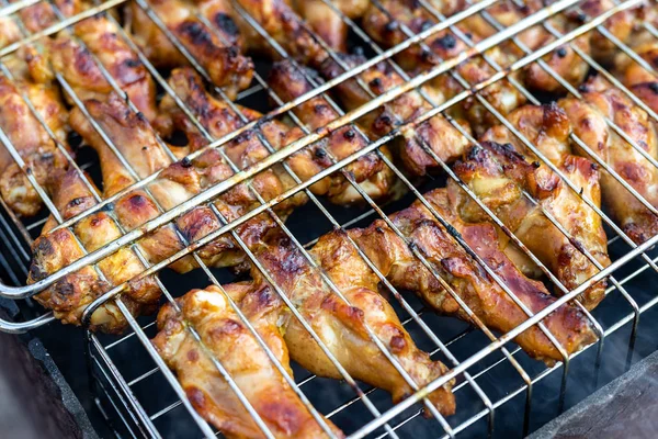 Close-up chicken wings cooking in metal barbecue grid on grill brazier. Outdoors weekend party on backyard. Tasty golden brown delicious bbq meal — Stock Photo, Image
