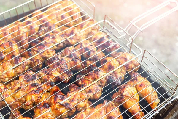 Крупный план куриные крылышки приготовления пищи в металлической решетке барбекю на гриле жаровня. Вечеринка на открытом воздухе на заднем дворе. Вкусная золотисто-коричневая барбекю — стоковое фото