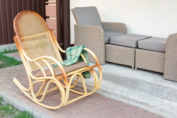 Cadeira de balanço de vime de madeira vazia com xadrez de flanela verde no quintal do terraço da casa ao ar livre. Estilo de vida tranquilo casa exterior — Fotografia de Stock