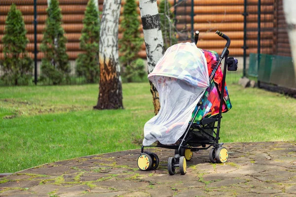 Gyermek babakocsiban, védőhálóval borítva séta közben. Babakocsi szúnyogellenes fehér takaróval. Midge-védelem a gyermekek számára a szabadtéri sétaszezonban — Stock Fotó