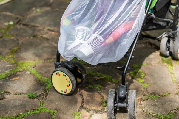 Gyermek babakocsiban, védőhálóval borítva séta közben. Babakocsi szúnyogellenes fehér takaróval. Midge-védelem a gyermekek számára a szabadtéri sétaszezonban — Stock Fotó