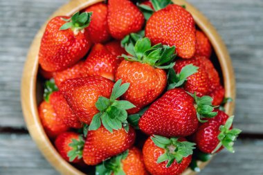 Bahçe veya arka bahçesinde ahşap yüzey açık havada ahşap kase tatlı taze sulu organik olgun çilek