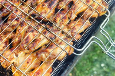 Izgara brazier üzerinde metal barbekü ızgara pişirme close-up üst görünüm tavuk kanatları. Arka bahçede açık hava hafta sonu partisi. Lezzetli altın kahverengi lezzetli barbekü yemek