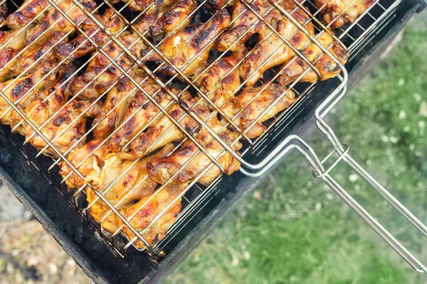 特写顶视图鸡翅在烤架上的金属烧烤网格烹饪。后院的户外周末派对。美味的金棕色美味烧烤餐 — 图库照片