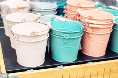 Ahşap masa açık havada satılık çeşitli çok renkli parlak küçük süs metal kovalar. Bahçe çiçek bitkileri için birçok renkli dekoratif mini kovalar