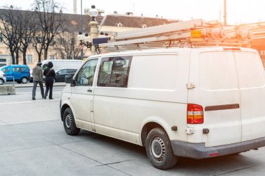 Beyaz tamir ve servis minibüsü merdiven ve turuncu ışık çubuğu şehir caddesinin çatısında. Yardım veya kurulum ekibi aracı