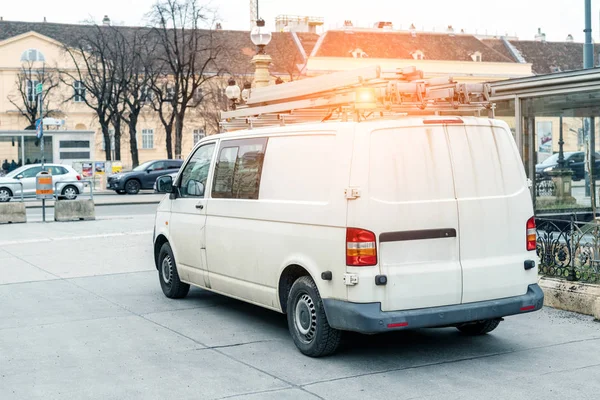 Wit reparatie- en servicebusje met ladder en oranje lichtbalk op het dak aan de stadsstraat. Assistentie of installatie team voertuig — Stockfoto