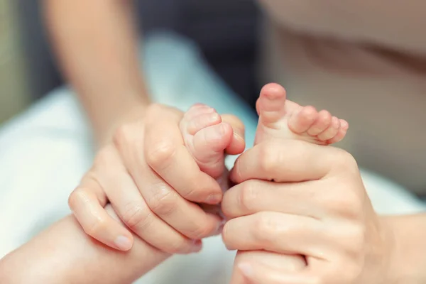 Anne yeni doğmuş bebek için bebek ayaklarına masaj yapıyor. Anne kucuk oglunun bacaklarina masaj yapiyor. Çocuk sagligi ve mutlu bir ebeveyn. — Stok fotoğraf