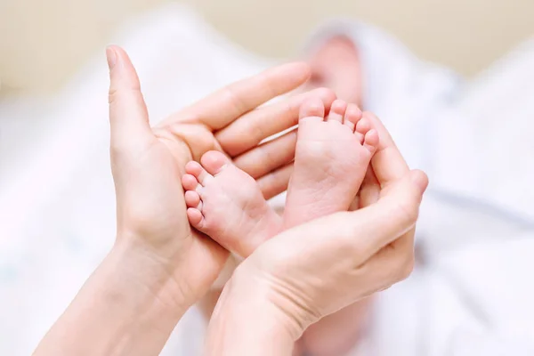 Mother holding newborn baby feet in hands. Mom taking care about infant child after taking bath. Parents childcare. Children healthcare and happy family — Stock Photo, Image