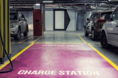 Alışveriş merkezi veya ofis binasının yeraltı kapalı otopark Elektrikli araba şarj istasyonu. Hızlı şarj fişleri ile çevre dostu yeşil enerji sıfır emiision araçlar için ayrılmış otopark