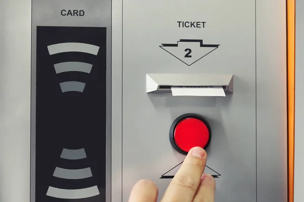Mano del hombre pulsando el botón rojo para recibir el billete en la entrada del aparcamiento. Máquina terminal de impresión de billetes con tecnología de acceso inalámbrico a tarjetas —  Fotos de Stock